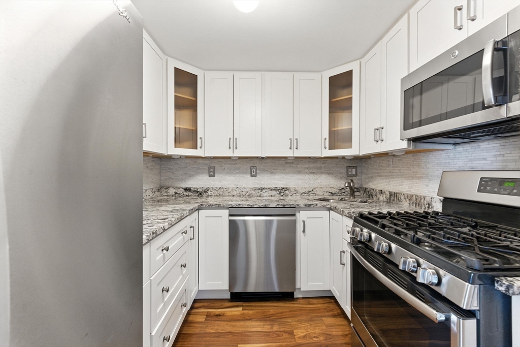 22 Chestnut Place, Unit 608 Brookline, MA 02445 - Photo 4 of 29 a kitchen with stainless steel appliances granite countertop a stove and a microwave