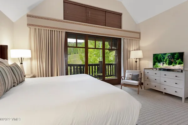 a bedroom with a bed and large windows