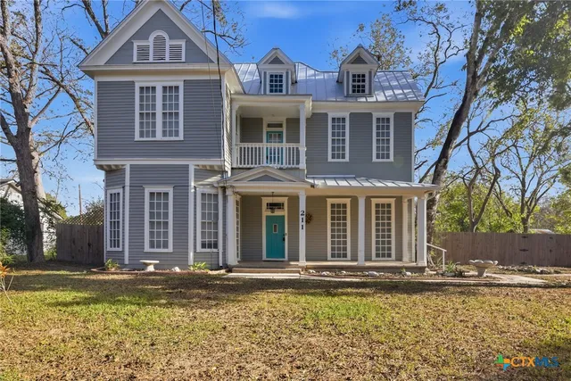 a view of a brick house with large windows and a table and chairs in a yard