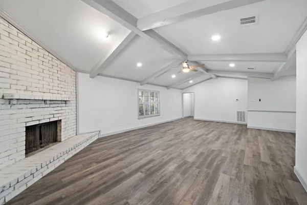 an empty room with wooden floor fireplace and windows