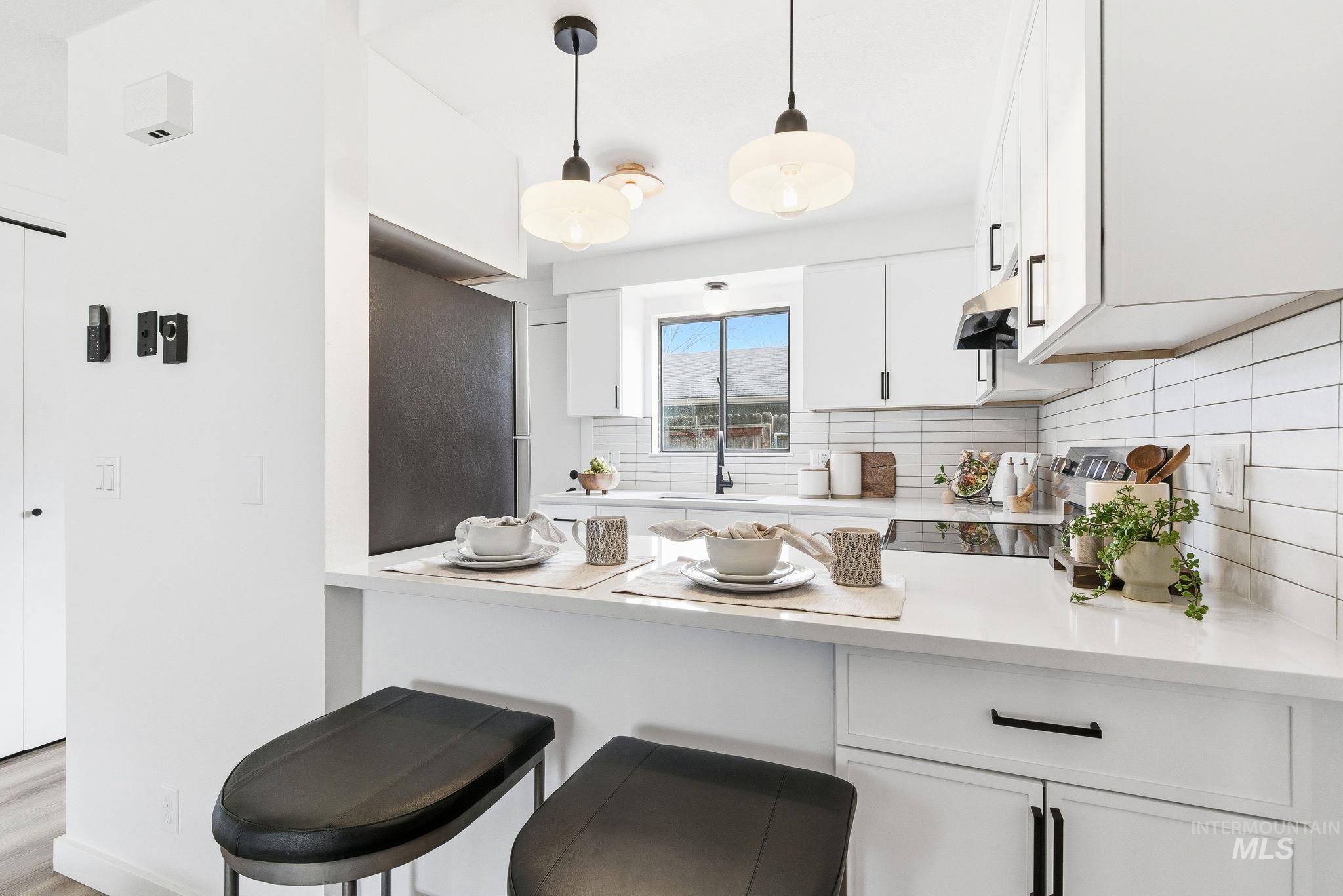 8443 West Rifleman Street Boise, ID 83704 - Photo 12 of 39 Kitchen featuring white cabinetry, a kitchen breakfast bar, a peninsula, pendant lighting, and decorative backsplash