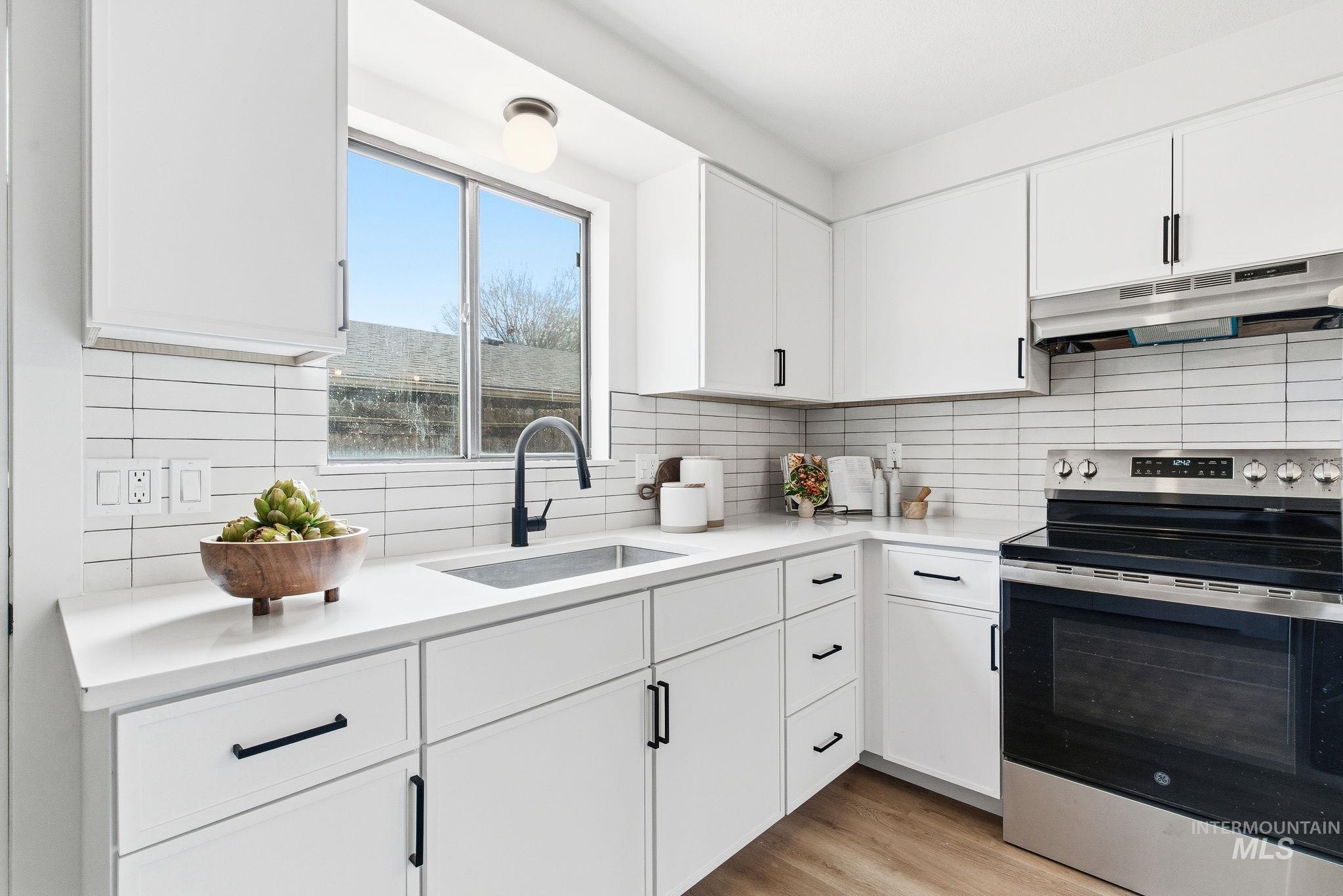 8443 West Rifleman Street Boise, ID 83704 - Photo 14 of 39 Kitchen with electric stove, white cabinetry, decorative backsplash, and light wood-type flooring
