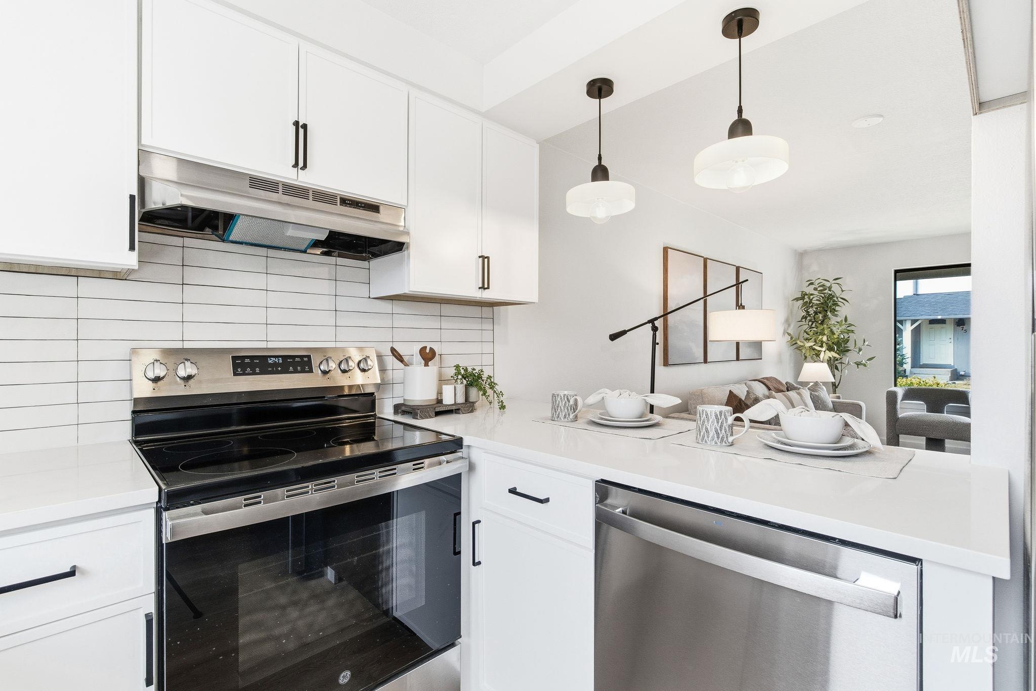 8443 West Rifleman Street Boise, ID 83704 - Photo 17 of 39 Kitchen with stainless steel appliances, white cabinets, backsplash, and decorative light fixtures