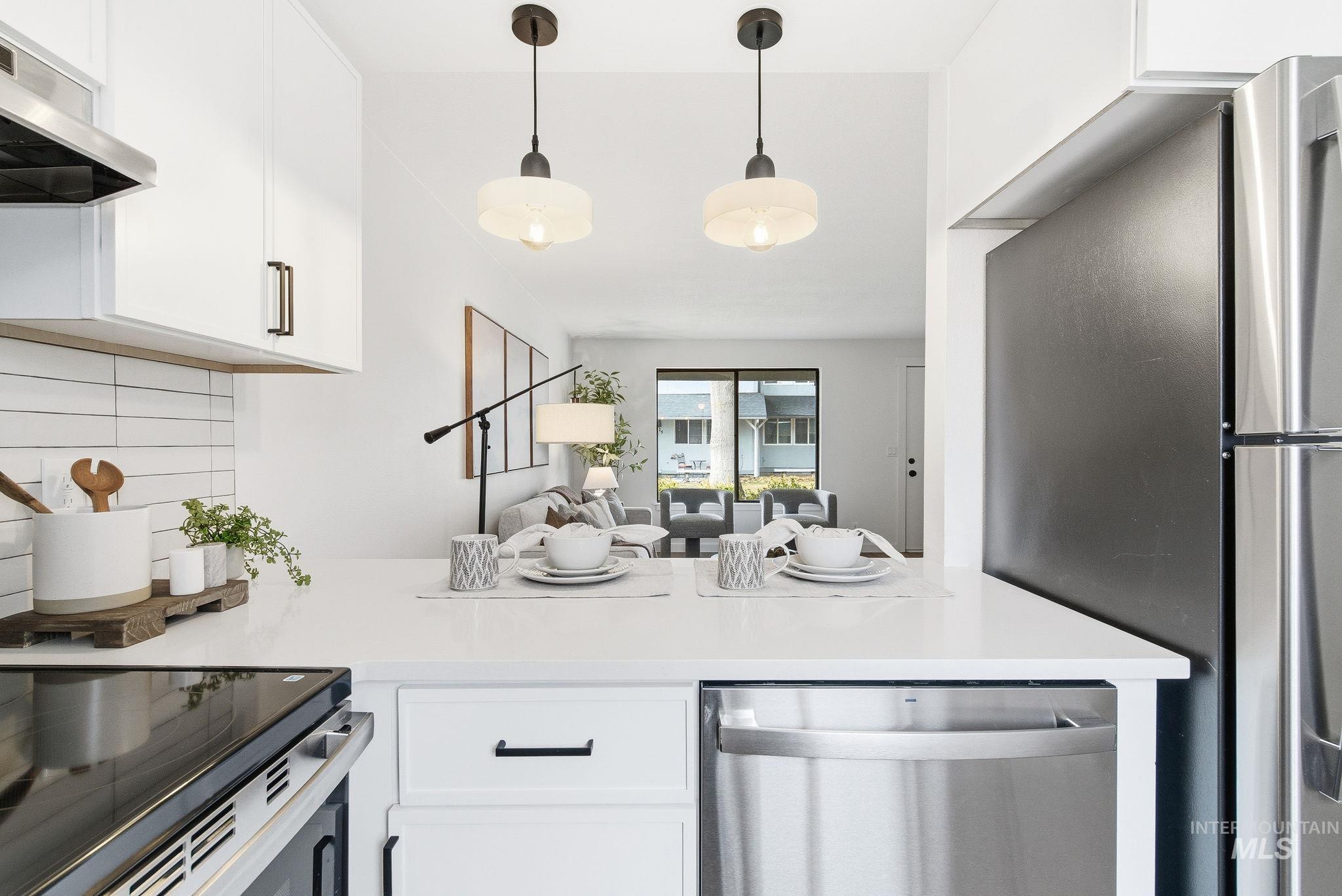 8443 West Rifleman Street Boise, ID 83704 - Photo 39 of 39 Kitchen with stainless steel appliances, tasteful backsplash, white cabinetry, open floor plan, and decorative light fixtures