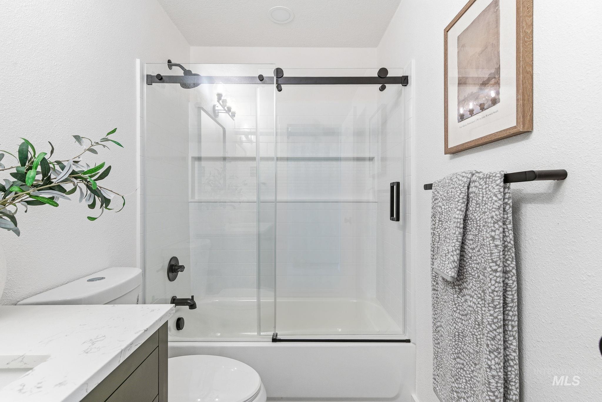 8443 West Rifleman Street Boise, ID 83704 - Photo 27 of 39 Bathroom with vanity, shower / bath combination with glass door, and a textured wall