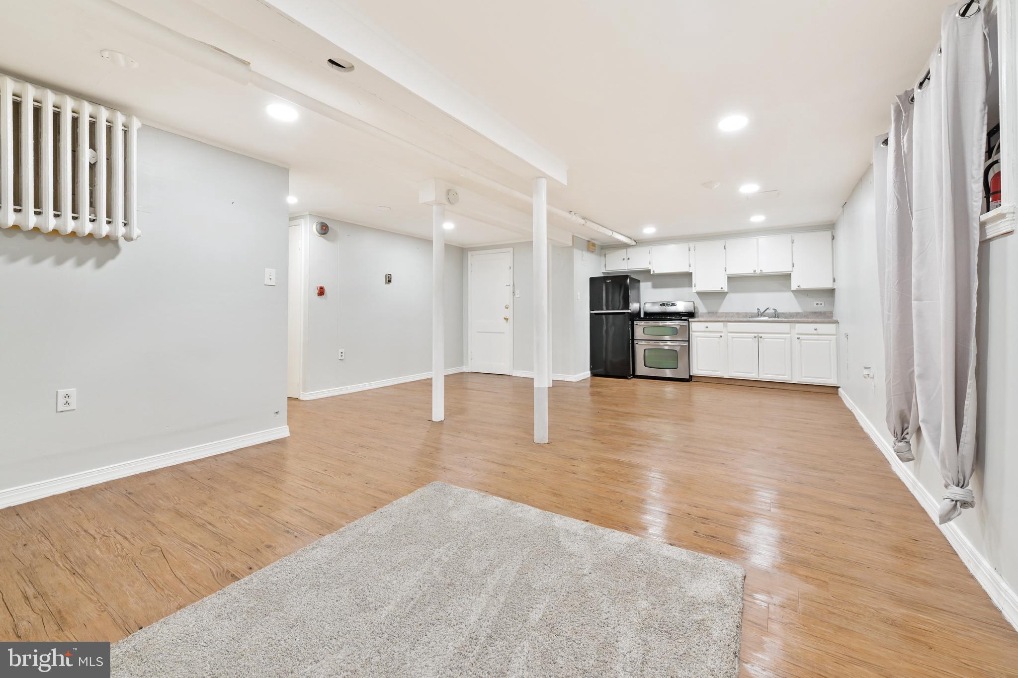 101 East 33rd Street, Unit B Baltimore, MD 21218 - Photo 2 of 7 an empty room with kitchen view and wooden floor