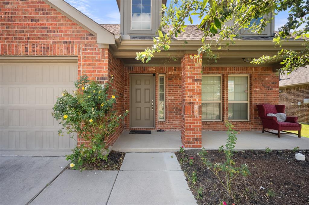 520 Rustic Oak Lane McKinney, TX 75072 - Photo 3 of 30 Brick exterior facade with a covered porch featuring a solid front door, sidelight window, and dual pane windows