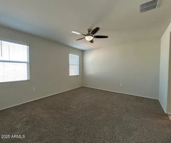 an empty room with windows and fan