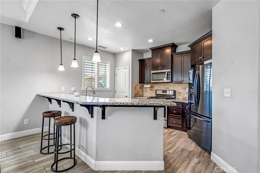 294 Double Tree Court Madera, CA 93637 - Photo 13 of 40 a kitchen with stainless steel appliances granite countertop a kitchen island hardwood floor and a sink