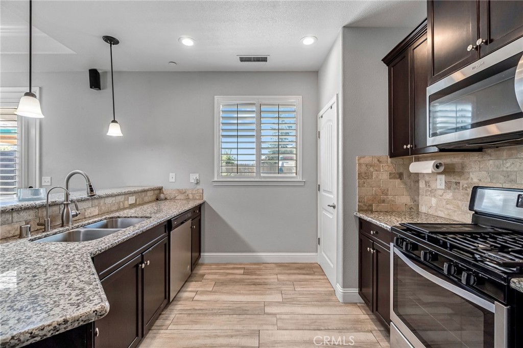 294 Double Tree Court Madera, CA 93637 - Photo 14 of 40 a large kitchen with stainless steel appliances granite countertop a stove a sink and a microwave