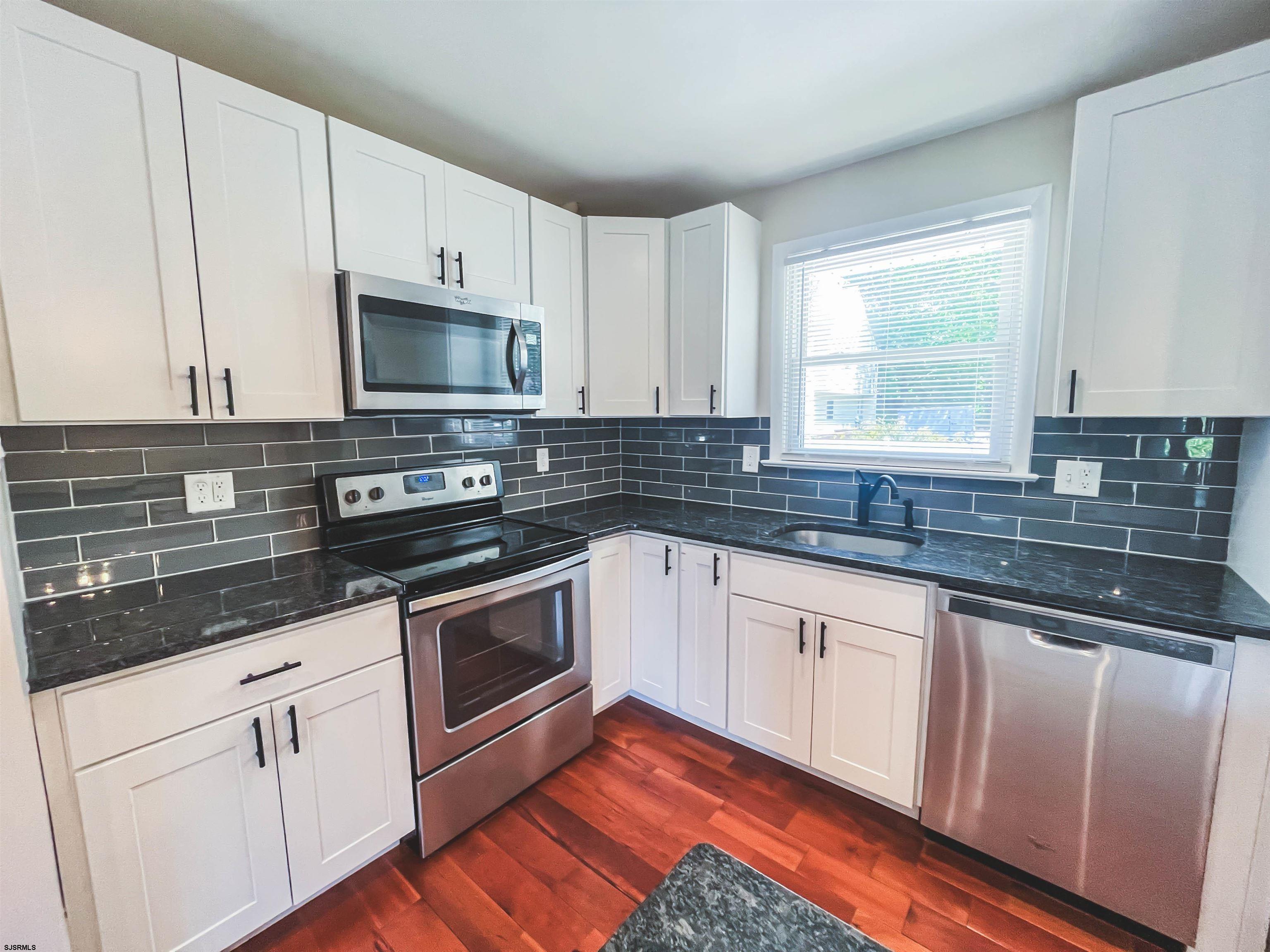 518 Delaware Avenue Absecon, NJ 08201 - Photo 7 of 38 a kitchen with granite countertop white cabinets appliances a sink and a window