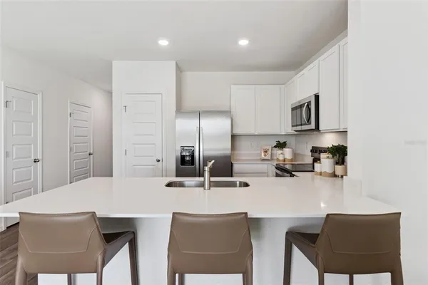 a kitchen with stainless steel appliances a dining table chairs microwave and sink