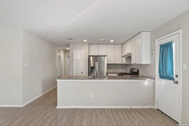 a large white kitchen with wooden floor and a sink