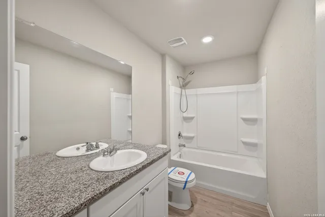 a bathroom with a granite countertop sink a toilet and shower