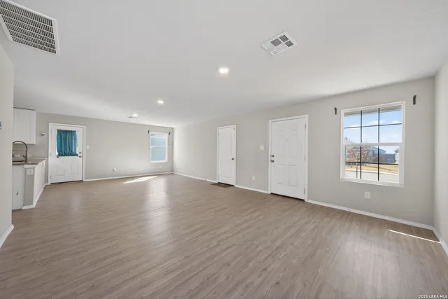 an empty room with wooden floor and windows
