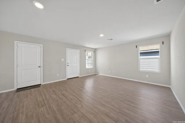 a view of an empty room with wooden floor and a window