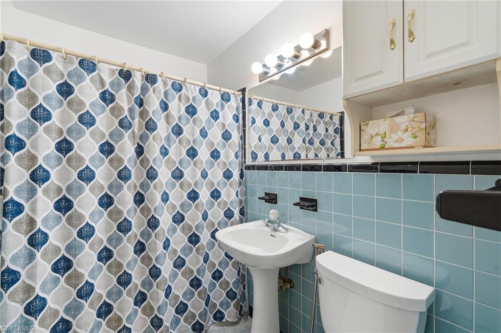 1316 Rordon Avenue Naples, FL 34103 - Photo 26 of 38 Bathroom featuring light blue wall tiles, a pedestal sink, and a white toilet