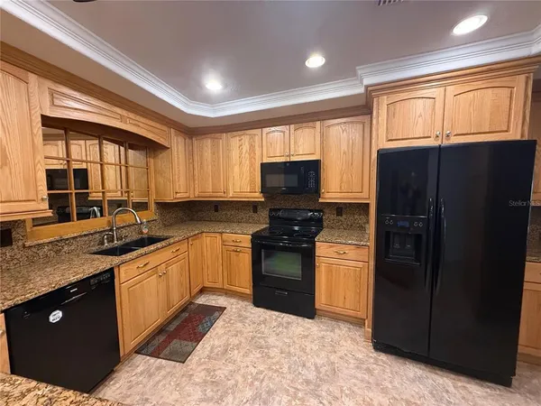 a kitchen with stainless steel appliances granite countertop a refrigerator a sink dishwasher a stove and black cabinets