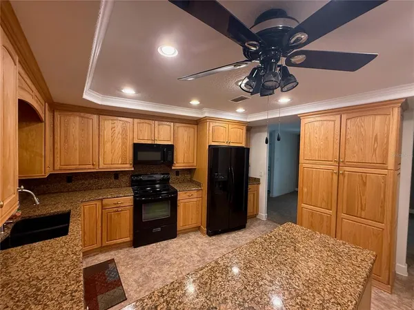 a kitchen with stainless steel appliances granite countertop a refrigerator a stove a sink and a microwave