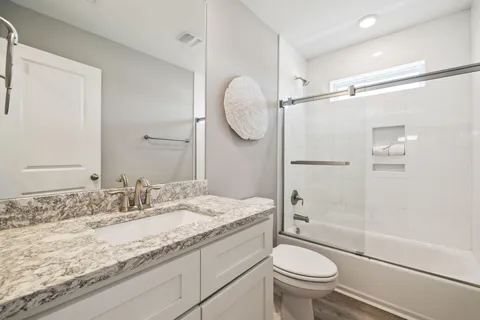 a bathroom with a granite countertop sink toilet mirror and shower