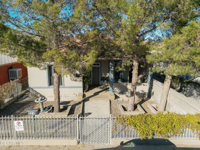 a view of a house with large trees and plants