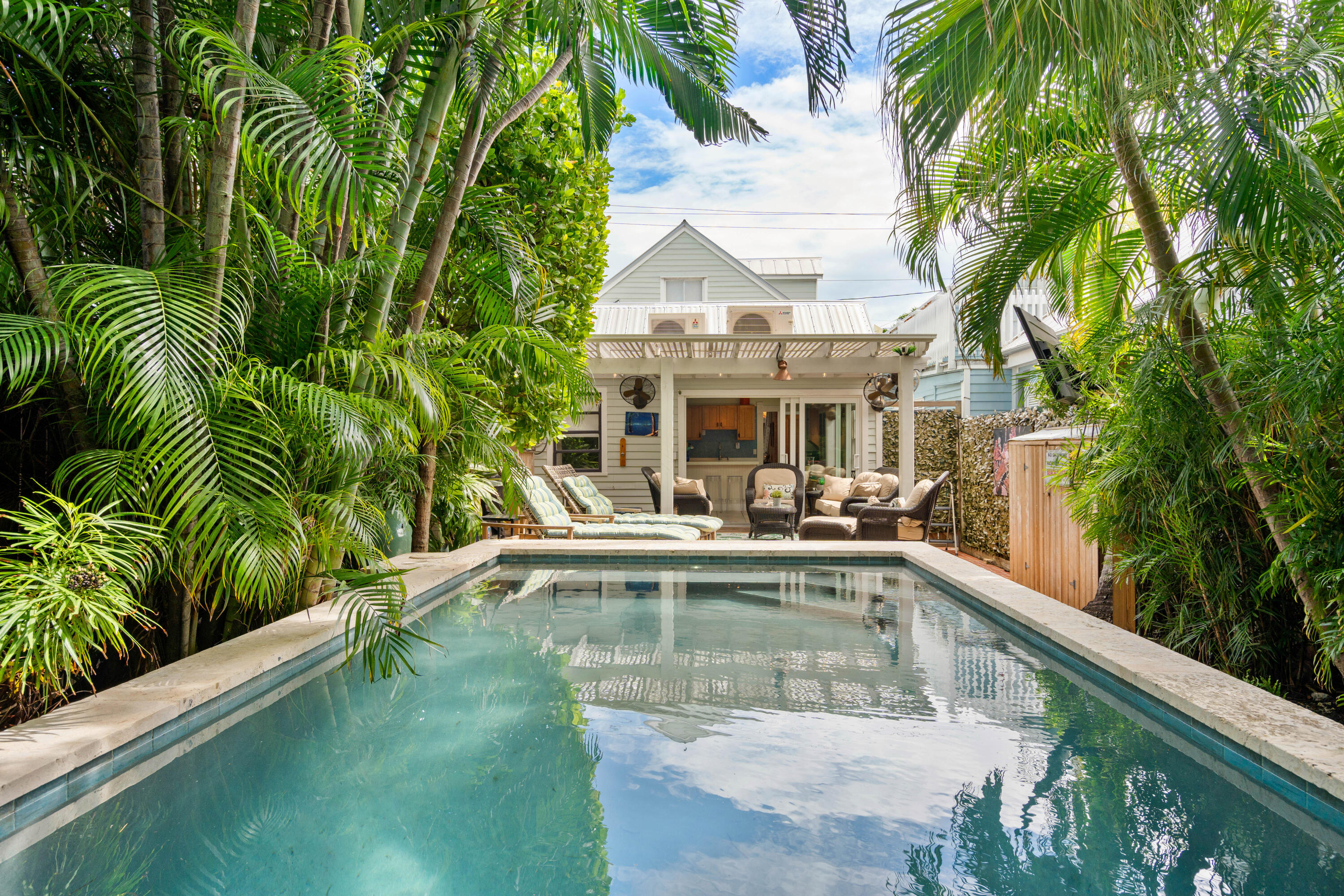 a view of a white house with a swimming pool and sitting area