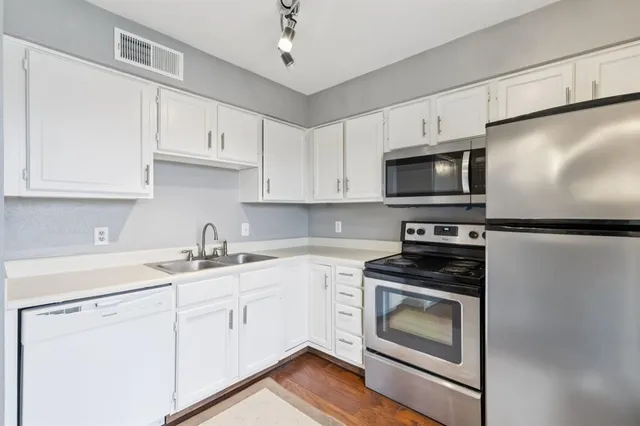 a kitchen with cabinets stainless steel appliances and wooden floor