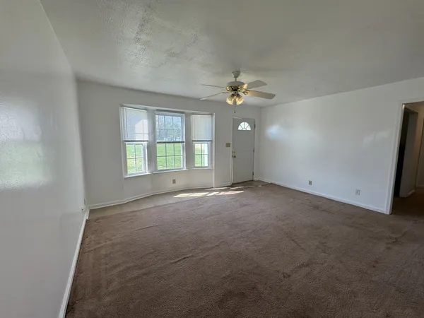 an empty room with windows and chandelier fan