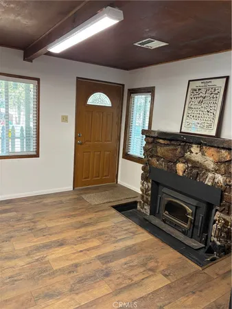 a living room with stainless steel appliances furniture a fireplace and a window