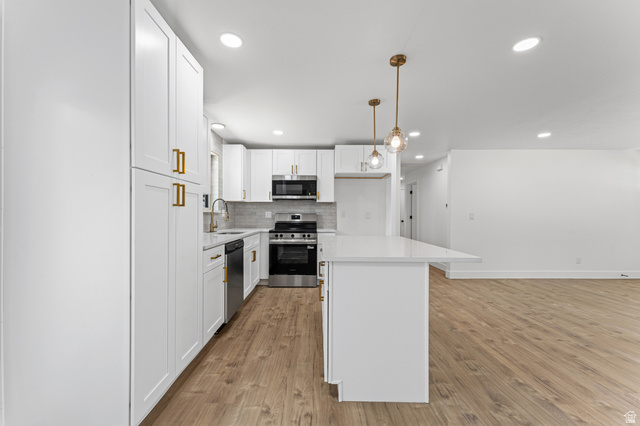 1898 West 600 South Provo, UT 84601 - Photo 6 of 32 Modern kitchen featuring white shaker cabinetry, stainless steel appliances, a white island with pendant lighting, and wood-finish flooring