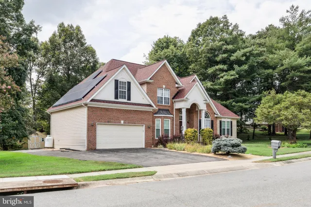 a front view of a house with a garden and trees