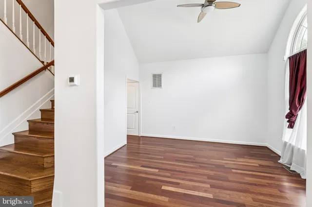 an empty room with wooden floor door and windows