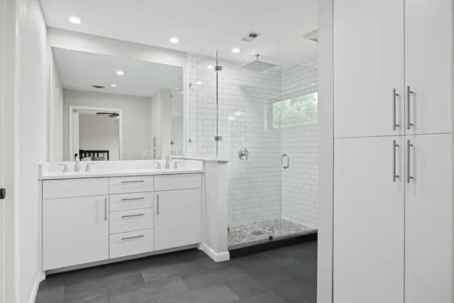 a bathroom with a double vanity sink a large mirror and shower