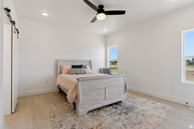 5777 West 4100 South Hooper, UT 84315 - Photo 12 of 41 Bedroom with a barn door, light wood-style floors, ceiling fan, and recessed lighting