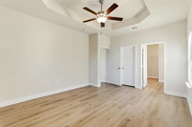 an empty room with wooden floor and a ceiling fan