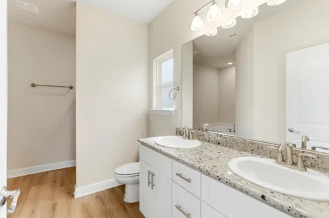 a bathroom with a granite countertop sink a toilet and a mirror