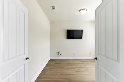 a view of room with wooden floor and flat screen tv