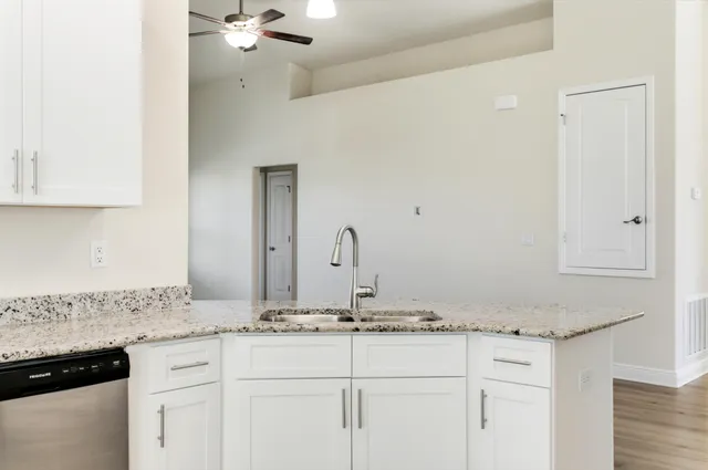 a bathroom with granite countertop white cabinets and a sink