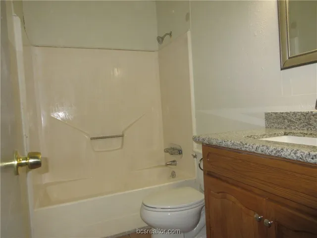 a bathroom with a granite countertop bathtub shower sink vanity and toilet