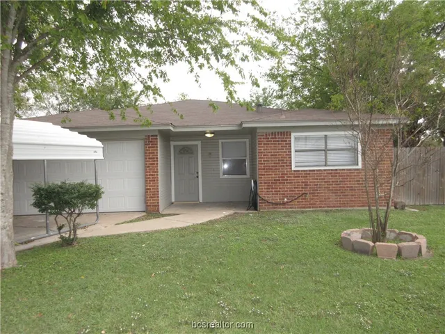 a front view of a house with a garden and trees