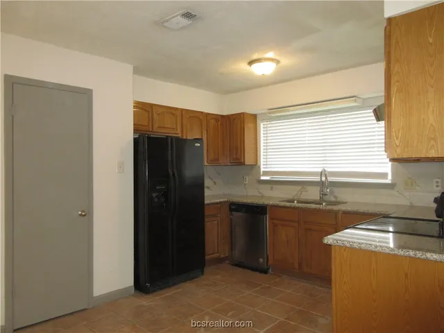a kitchen with granite countertop a refrigerator and a sink