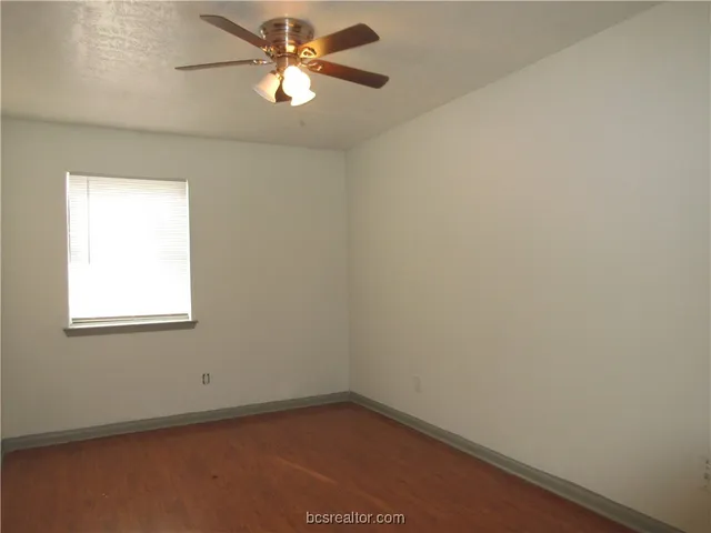 an empty room with a window and a fan