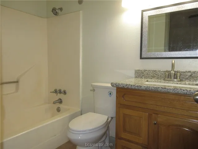 a bathroom with a granite countertop toilet sink and mirror