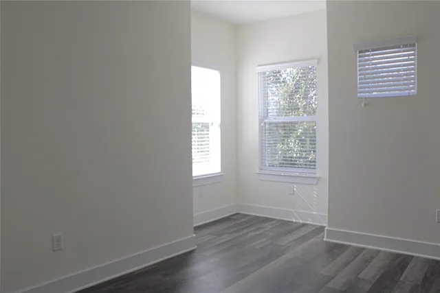 an empty room with wooden floor and a ceiling fan