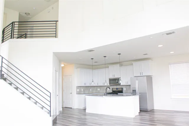 a kitchen with stainless steel appliances granite countertop a refrigerator sink and white cabinets
