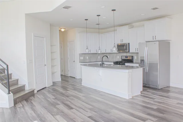 a kitchen with stainless steel appliances white cabinets and wooden floor