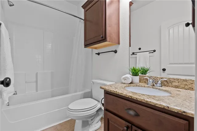 a bathroom with a granite countertop sink a toilet and bathtub