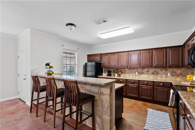 a kitchen with stainless steel appliances granite countertop table chairs sink and cabinets