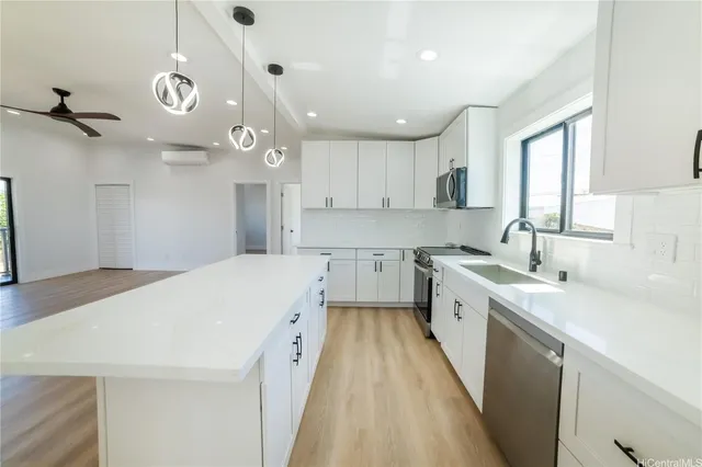 a large white kitchen with a large window a sink and stainless steel appliances