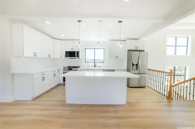 a view of kitchen with stainless steel appliances granite countertop a stove top oven a sink a refrigerator and white cabinets